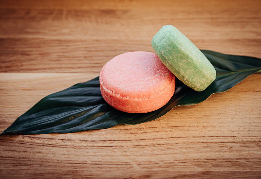 Pink and green color solid shampoo bars on leaf.